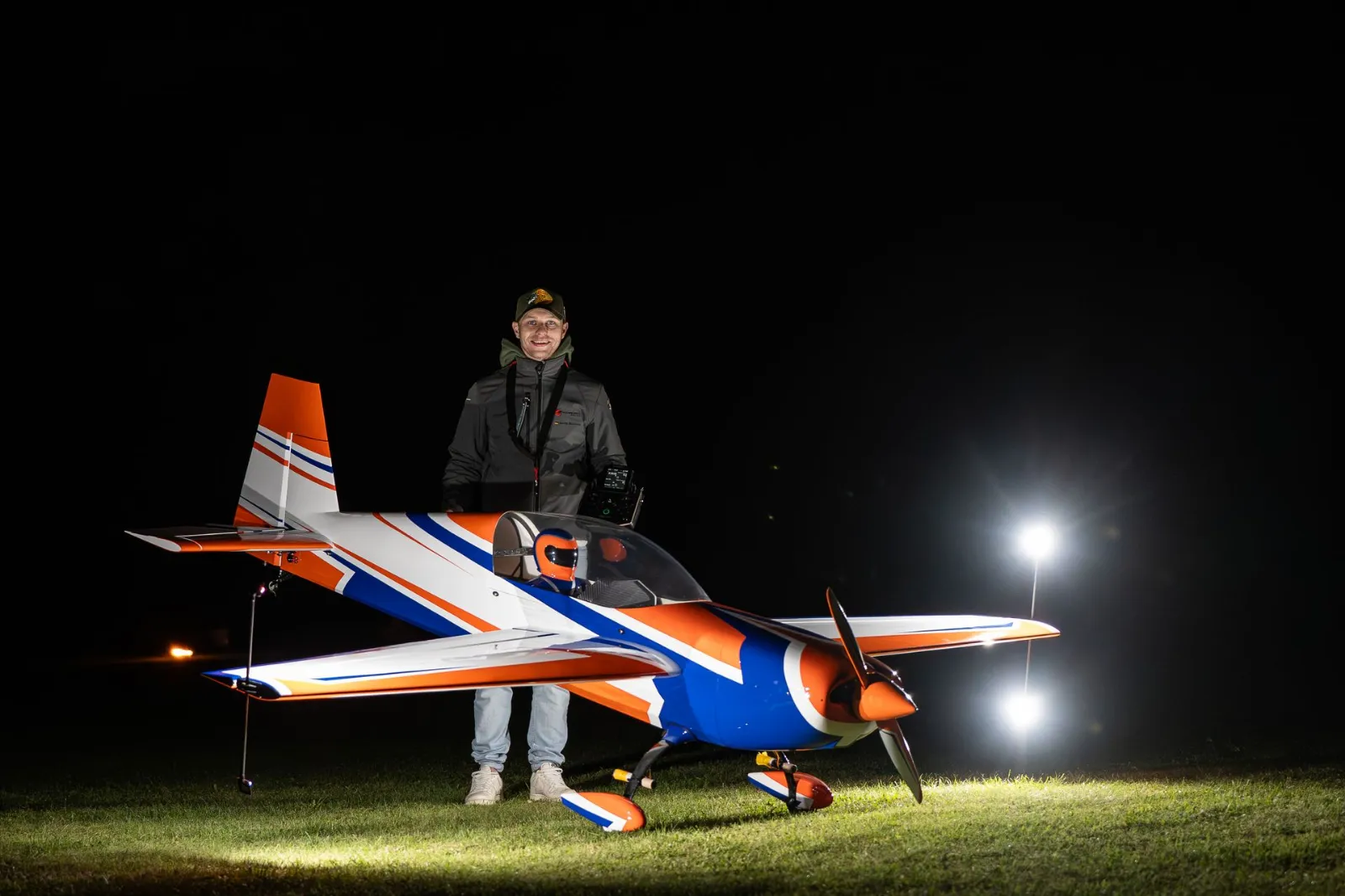 Pilot neben beleuchtetem Kunstflugmodell auf dem Flugfeld